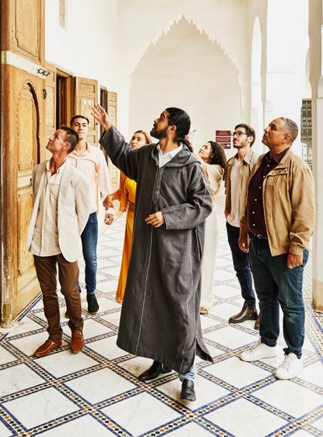 Visite guidée en groupe dans un site culturel historique, guide expliquant l’architecture.