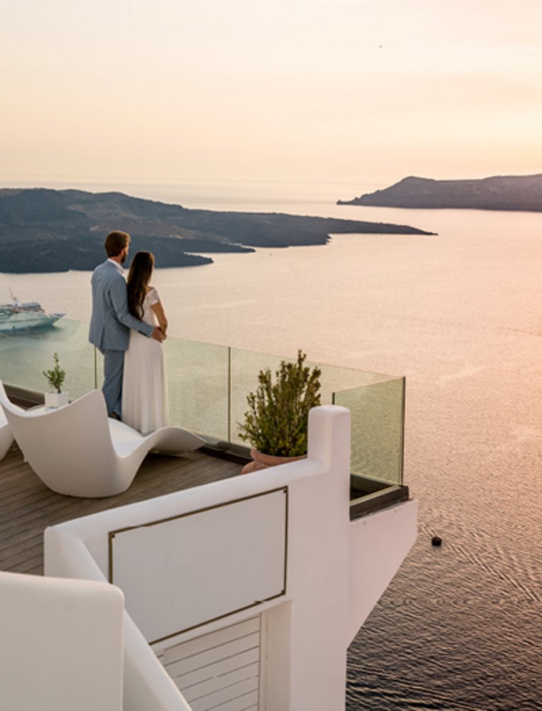 Un couple se tient sur un balcon et contemple la mer, entouré par l'atmosphère romantique des îles grecques.
