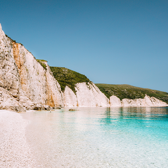 Küstenlandschaft in Griechenland mit weißen Klippen und türkisblauem Meer, Badeferien buchen.