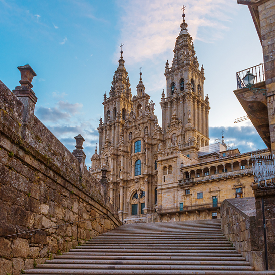 Grosses Gebäude mit Uhrturm und Treppen in Santiago de Compostela.