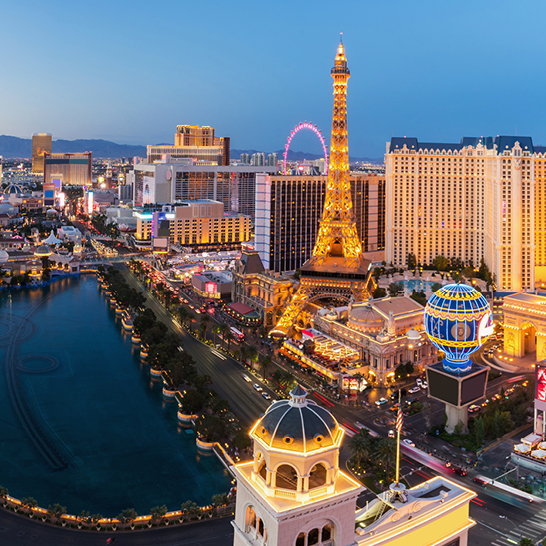 Vue du Strip de Las Vegas au crépuscule, illuminé par des néons et des lumières scintillantes.