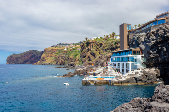 Vue de la mer sur le bâtiment principal et la piscine de l'hôtel
